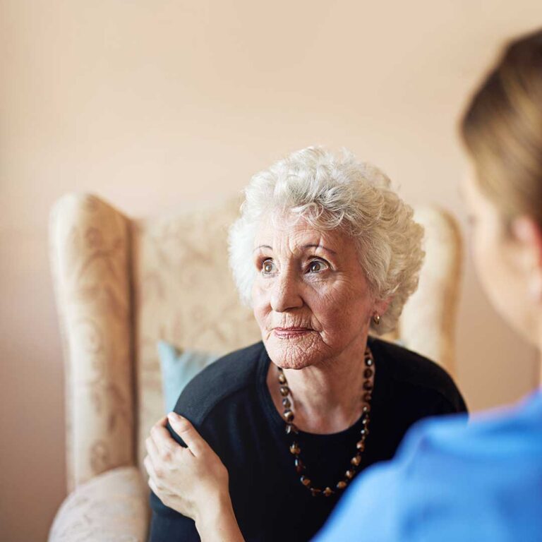 Older adults unpacking boxes and arranging personal items in a cozy assisted living apartment.