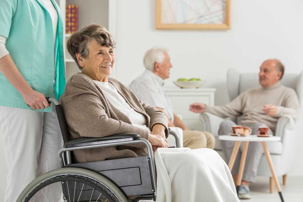 Elderly residents sharing a meal and engaging in conversation around a decorated dining table.