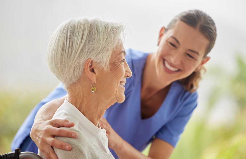 Resident and caregiver having a calm conversation in a bright assisted living common room.